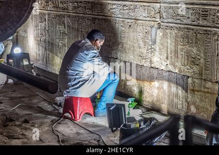 Restauratoren arbeiten an der Reparatur und Wiederherstellung der alten ägyptischen Steinmauern mit Hieroglyphen und Reliefskulptur an einem historischen Ort bedeckt. Stockfoto