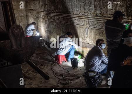 Restauratoren arbeiten an der Reparatur und Wiederherstellung der alten ägyptischen Steinmauern mit Hieroglyphen und Reliefskulptur an einem historischen Ort bedeckt. Stockfoto