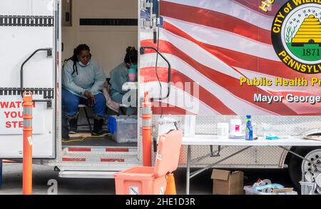 Wilkes Barre, Usa. 06th Januar 2022. Mitarbeiter im Gesundheitswesen machen eine Pause, um mehr Energie zu erhalten, um die langen Warteschlangen zu beenden, die darauf warten, getestet zu werden. Mit der neuen Omicron-Variante Covid-19-Überspannung sehen Teststandorte lange Testreihen. Mitarbeiter von AMI Expeditionary Healthcare werden in Pennsylvania bei Covid-19-Tests beobachtet. Die Gruppe ist von Hotel zu Hotel gewechselt und arbeitet 12 Stunden an 4-5 Tagen in der Woche, um Community-Mitglieder auf Covid-19 zu testen. (Foto von Aimee Dilger/ SOPA Images/Sipa USA) Quelle: SIPA USA/Alamy Live News Stockfoto