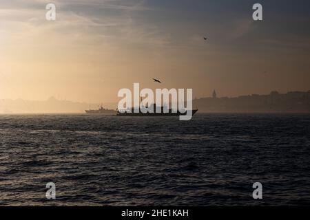 Moody Istanbul Hintergrund. Silhouette von Fähre und Stadtbild von Istanbul. Galata Turm und Moscheen. Stockfoto