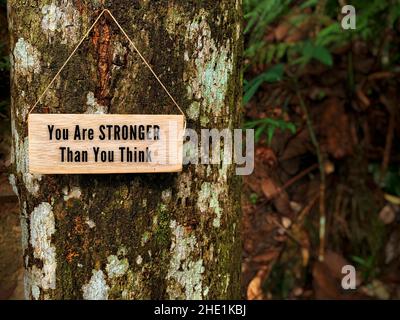 Motivierende und inspirierende Zitate auf Holzklotz - Sie sind stärker, als Sie denken. Mit Baum und Natur Hintergrund. Stockfoto