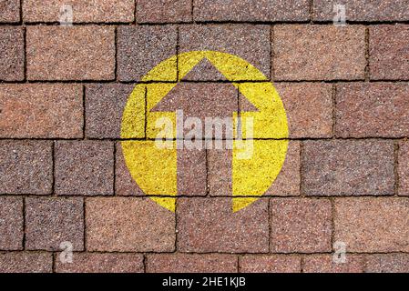 Pfeil-Symbol zeigt nach oben in gelber Farbe auf Sandsteinpflaster. Motivationssymbol. Stockfoto