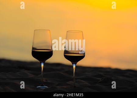 Rotweingläser am Strand bei Sonnenuntergang, Festkonzept Stockfoto