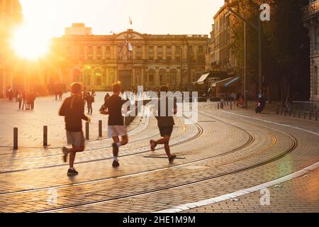 Bordeaux, Frankreich - 1. Oktober 2020 : Stadtstraßenszene mit verschwommenen Menschen, die während des Sonnenuntergangs in Bordeaux, Frankreich, vor dem Rathaus laufen Stockfoto