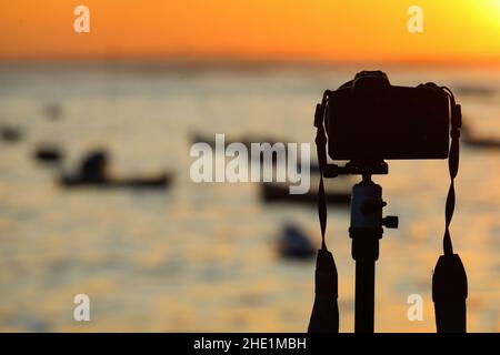 Kamera auf Stativ fotografieren bei Sonnenaufgang über dem Meer Stockfoto