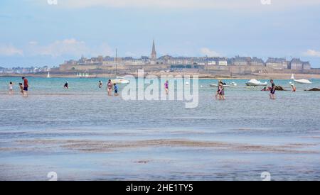 Saint Malo, Frankreich - 13. Juli 2017: Menschen, die bei Ebbe in der Bucht von St. Malo in der Bretagne spazieren gehen. St Malo, eine historische Stadt an der Atlantikküste, h Stockfoto