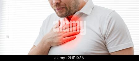 Der junge Mann leidet unter Sodbrennen. Erkrankung des Magen-Darm-Traktes. Halsschmerzen. Stockfoto