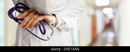 Arzt mit Stethoskop. Auf dem Hintergrund des verschwommenen Krankenhauskorridors. Stockfoto