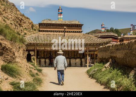 XIAHE, CHINA - 24. AUGUST 2018: Die Menschen gehen auf dem Pilgerweg der inneren Kora um das Labrang Kloster in der Stadt Xiahe, Provinz Gansu, China Stockfoto