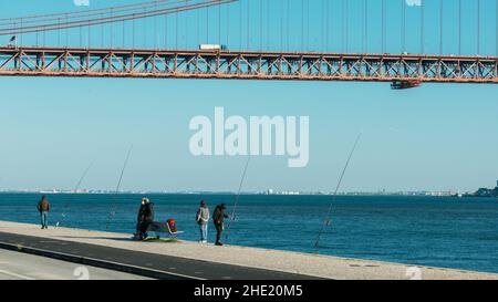 Lissabon, Portugal - 7. Januar 2022: Fischer auf einem Fluss Tejo in der Nähe der Brücke vom 25. April in Lissabon Stockfoto