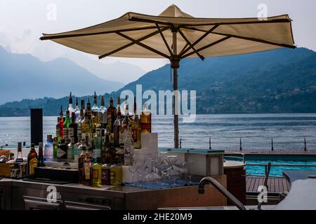Minibar mit Flaschen alkoholischer Getränke und Sonnenschirm am Seeufer des Grand Hotel Tremezzo. Stockfoto
