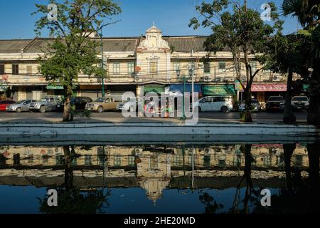 Ein Tuk-Tuk, der an malerischen alten Lagerhäusern und Geschäften entlang der Atsadang Road entlang des Klong (Kanal) Lod im historischen Stadtgebiet von Bangkok, Thailand, vorbeiführt Stockfoto