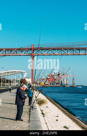 Lissabon, Portugal - 7. Januar 2022: Fischer auf einem Fluss Tejo in der Nähe der Brücke vom 25. April in Lissabon Stockfoto