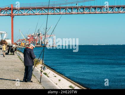 Lissabon, Portugal - 7. Januar 2022: Fischer auf einem Fluss Tejo in der Nähe der Brücke vom 25. April in Lissabon Stockfoto