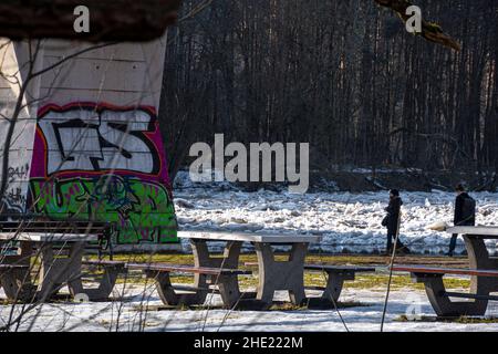 Menschen, die an Bänken gegen ein Graffiti-Gemälde unter einer Fußgängerbrücke in Litauen gehen Stockfoto