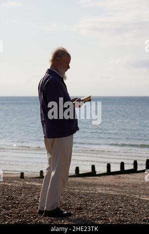 Mann sah ein Buch lesen, während er am Strand von Bognor Regis, Großbritannien, stand. Stockfoto