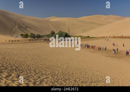 DUNHUANG, CHINA - 21. AUGUST 2018: Touristen in der Singing Sands Düne in der Nähe von Dunhuang, Provinz Gansu, China Stockfoto