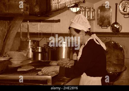 Regensburg, Bayern, Deutschland - 11.11.2014: Eine Frau bereitet traditionelle deutsche Grillwürste zu. Gashtet in der Altstadt. Stockfoto