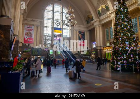 Ukraine, Kiew - 7. Januar 2022: Bahnhofsgebäude im Inneren. Halle mit Weihnachtsbaum, Rolltreppe und Menschen mit Koffern reisen und warten auf ihren Zug. Reisende am Bahnhof Stockfoto