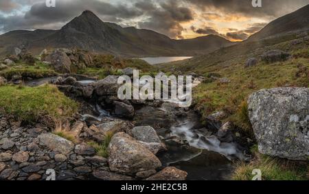 Episch dramatische Landschaftsaufnahme von Llyn Ogwen und Tryfan im Snowdonia National Park mit Bach und Felsen im Vordergrund Stockfoto