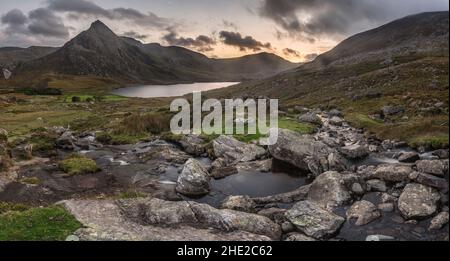 Episch dramatische Landschaftsaufnahme von Llyn Ogwen und Tryfan im Snowdonia National Park mit Bach und Felsen im Vordergrund Stockfoto