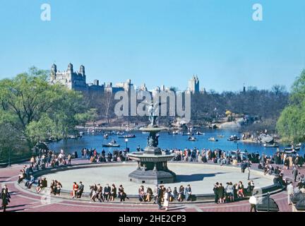 Ein Blick von der Bethesda-Terrasse auf den (trockenen) Bethesda-Brunnen im Central Park, New York City in der frühen Frühlingssonne von 1946. Viele Besucher genießen die Einrichtungen und es gibt viele Boote auf dem See. Bethesda Terrasse und Brunnen bilden das nördliche Ende des Parks. Der Bethesda-Brunnen ist das zentrale Merkmal auf der unteren Ebene der Terrasse. Der Pool wird von einer Brunnenskulptur dominiert, die Emma Stebbins entworfen und 1873 enthüllt hat – einem Vintage-Foto aus dem Jahr 1940s. Stockfoto