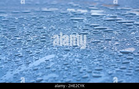 Wassertropfen auf dem Dach, ein blaues Auto Stockfoto