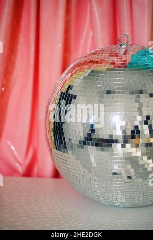 Große glänzende reflektierende Spiegel silber funkelnden Nachtleben Disco Ball vor farbenfrohem Hintergrund reflektiert helle Lichter, vertikale Aufnahme. Party-Design Stockfoto