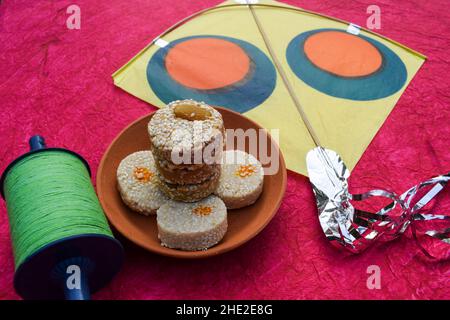 Indisches Sankrant Festival süßes Element namens Til Baati Sesam Samen bati mit Kite Festival Thema Hintergrund Poster. Zwei Typen Til gud bati und Til mawa Stockfoto