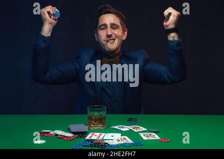 Glücklicher Pokerspieler, der mit Pokerkarten und Chips gewinnt. Stockfoto