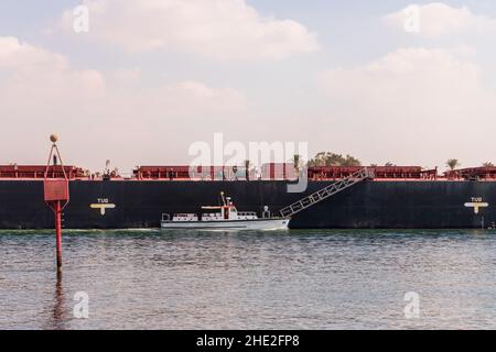 Pilotboot und Frachtschiff sind unterwegs am Suez-Kanal, Ismailia, Ägypten Stockfoto