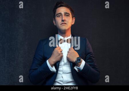 Junger Geschäftsmann in Anzug vor grauem Hintergrund. Stockfoto