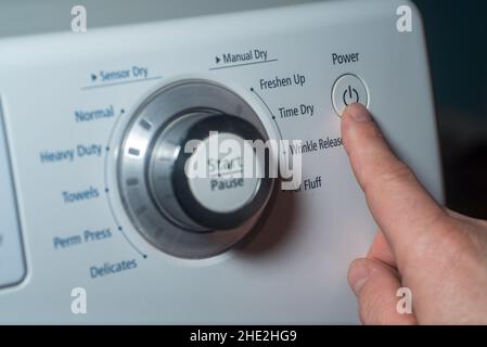 Drücken Sie den Netzschalter am elektrischen Trockner mit dem Finger Stockfoto