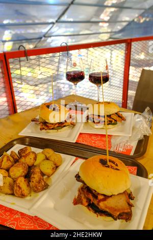 dezember 2021 Florenz, Italien: Hamburger, rustikale Kartoffeln, Rotwein auf dem Food Court des zentralen Marktes von Florenz, mercato centrale Stockfoto