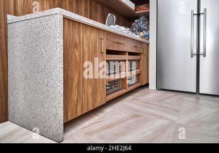 Holzschrank mit Schubladenkörben und solider Acryl-Arbeitsplatte in hellem Lebensmittellagerraum der Wohnung Blick in die Nähe Stockfoto