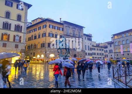 Dezember 2021 Florenz, Italien: Das Reiterdenkmal von Cosimo Statue auf dem Platz, piazza della Signoria. Touristen wandern mit Sonnenschirmen in der Stockfoto