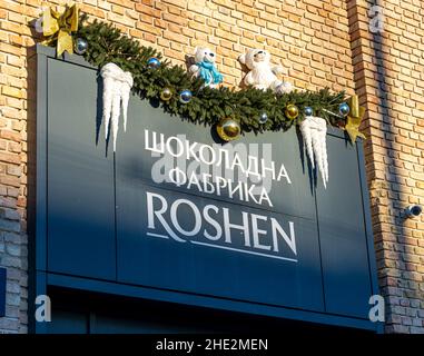 Ukraine, Kiew - 7. Januar 2022: Roshen Chocolate Factory. Haupteingang zum Gebäude und Schild-Logo. Süßwarenfabrik, Firmenzeichen Roshen. Stockfoto