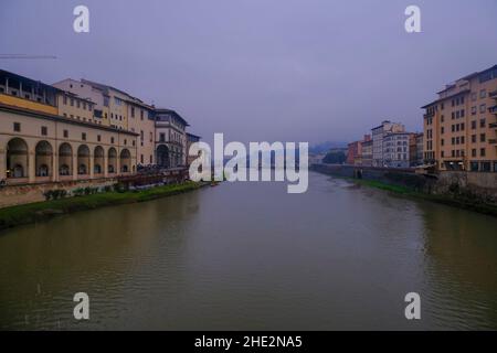 Florenz, Italien: Blick von der Ponte Vecchio in Florenz an einem regnerischen Tag auf den Fluss Arno, den Kanal und bunte Gebäude am Ufer Stockfoto