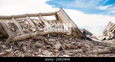 Panoramabilder Blick auf das einstürzende Industriegebäude mit mehreren Ebenen aus Beton. Katastrophenort voller Schutt, Staub und beschädigtem Haus. Stockfoto