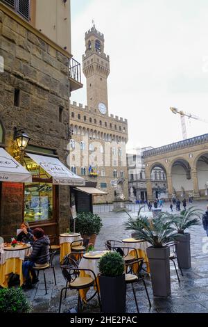 Dezember 2021 Florenz, Italien: Café mit Menschen auf dem Platz. piazza della Signoria gegenüber dem Turm des Palazzo Vecchio Stockfoto