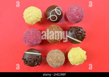 Pralinen aus Schokolade oben Ansicht Stock Bilder. Schokolade Bonbons auf rotem Hintergrund. Schokoladenrahmen Draufsicht. Quadratischer Schokoladenpralinen-Hintergrund Stockfoto
