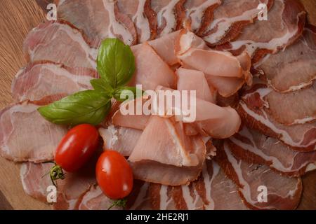 Italienische gehärtete Schweineschulter. Antipasto-Platte coppa stagionata und Kirschtomaten. Traditionelle Wurst in Scheiben mit Gewürzen Stockfoto