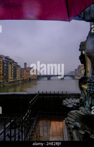 Florenz, Italien: Blick von der Ponte Vecchio in Florenz an einem regnerischen Tag über Regenschirm und Denkmal von Benvenuto Cellini Stockfoto