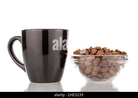 Mehrere duftende, frisch geröstete Kaffeebohnen in einer Glasschale mit schwarzer Keramikschale, Nahaufnahme, isoliert auf Weiß. Stockfoto