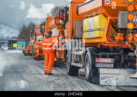 Liptovsky Hradok, Slowakei - 12. Februar 2020: Gruppe von hellorangen Straßenmeisterwagen mit Eisensalz, die sich im Winter vorbereiten, Schneekoje Stockfoto