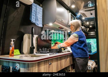 Frau kocht im Wohnmobil Airstream Interstate 24X 4WD; Ainsworth State Park; Columbia River Gorge; Oregon; USA Stockfoto