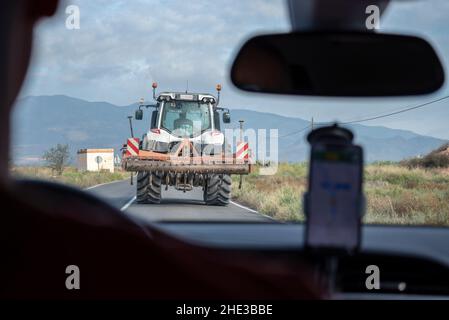 Fahren, stecken hinter einem Traktor auf einer Straße in Fuente Alamo, Murcia, Spanien, Europa. Landwirtschaftliches Fahrzeug, das eine schmale Landstraße blockiert Stockfoto