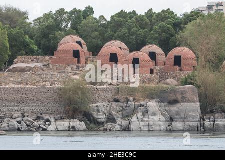 Rote Backsteinhäuser, die illegal entlang des Nils in Assuan, Ägypten, gebaut wurden und nun leer stehen und auf den Abriss warten. Stockfoto