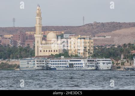 Eine große Moschee am Nilufer in Assuan, angedockte Kreuzschiffe stehen davor. Stockfoto