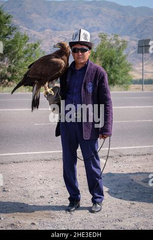 Kirgisischer Adlerjäger posiert mit Steinadler Stockfoto